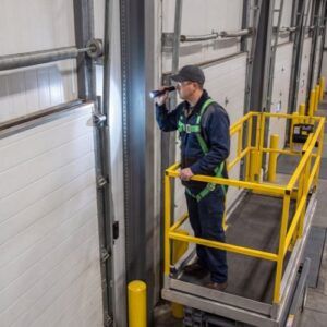 Technician inspecting a commercial loading dock door at a warehouse.