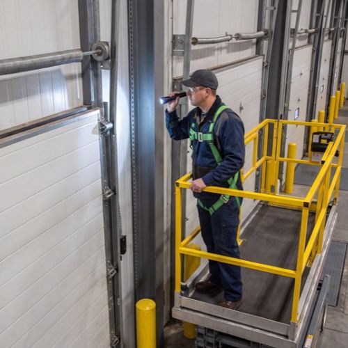 Technician inspecting a commercial loading dock door at a warehouse.